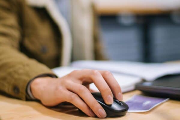 Worker using a computer with a focus on their hand on a wireless mouse.